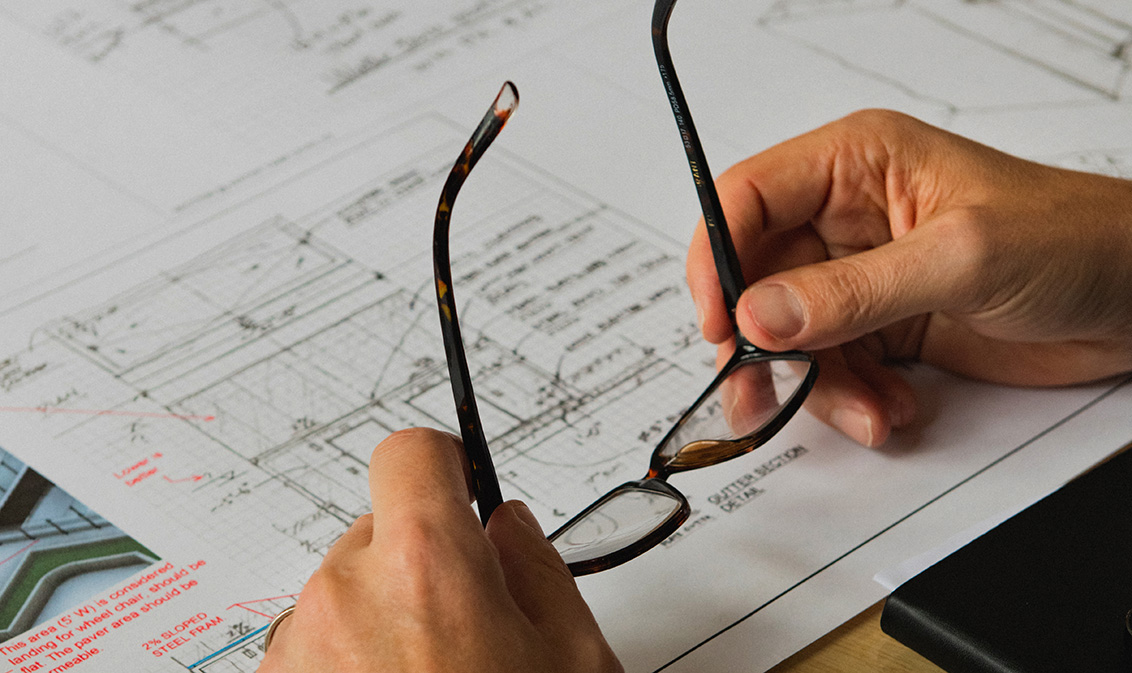 Holding glasses over building plans
